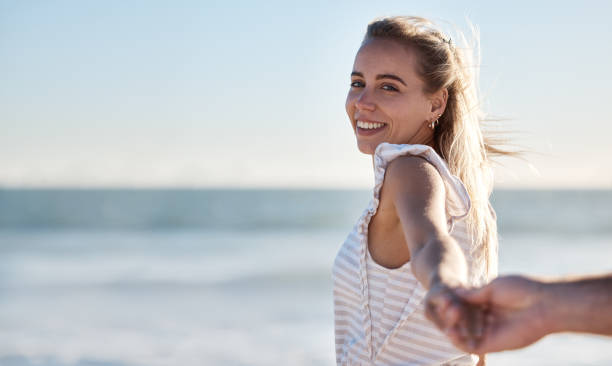 de mãos dadas, sorriso e casal caminhando na praia com apoio, amor e carinho em um feriado. verão, afeto e retrato de uma mulher com a mão de um homem para confiança, viagem e aventura pelo mar - trust human hand sea of hands holding - fotografias e filmes do acervo