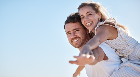 Love, blue sky and happy couple together for summer, holiday and outdoor wellness, date anniversary and freedom with mockup. Happy woman and man piggyback ride for support, care and healthy lifestyle