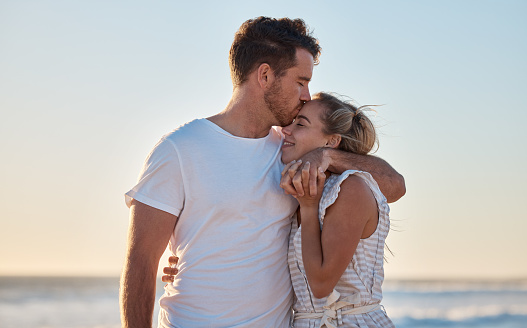 Happy, young couple in white summer clothes enjoying their vacation on a tropical beach