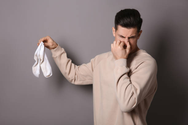 istock Man feeling bad smell from dirty socks on grey background 1456827827