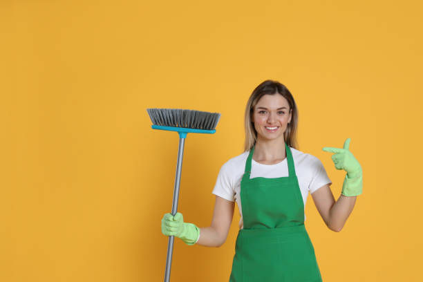istock Young woman with broom on orange background, space for text 1456829377
