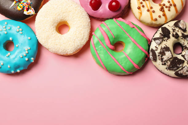 istock Different delicious glazed doughnuts on pink background, flat lay. Space for text 1456829699