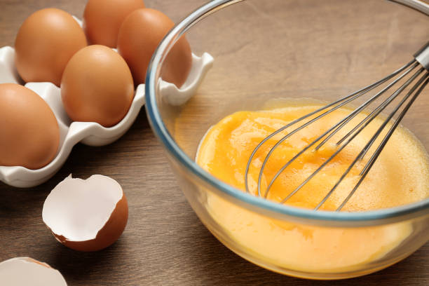 istock Whisking eggs in glass bowl on wooden table, closeup 1456831211