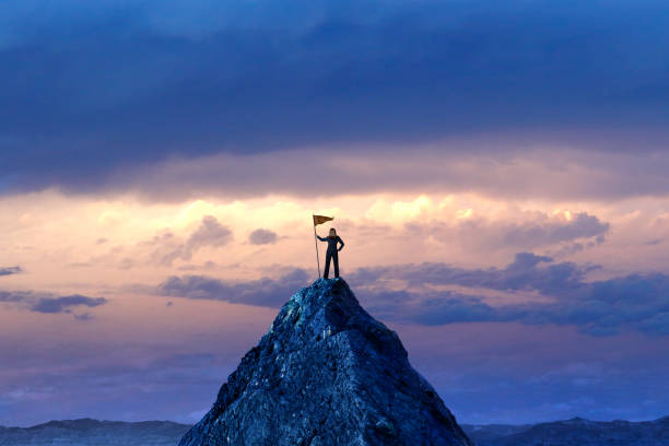 istock Woman Planting A Flag On A Mountain Peak 1456831358