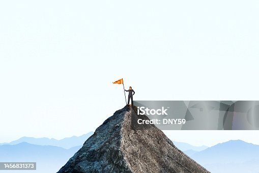 istock Woman Planting A Flag On A Mountain Peak 1456831373