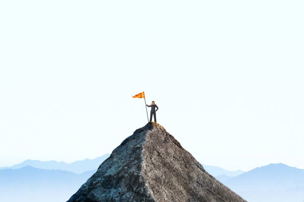 Woman Planting A Flag On A Mountain Peak stock photo