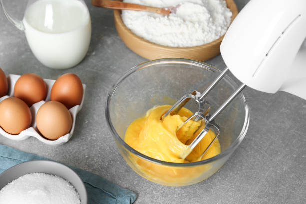 istock Beating eggs in glass bowl with mixer on light grey table 1456831563