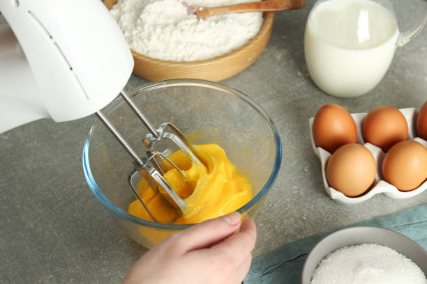 istock Woman beating eggs with mixer at light grey table, closeup 1456831958