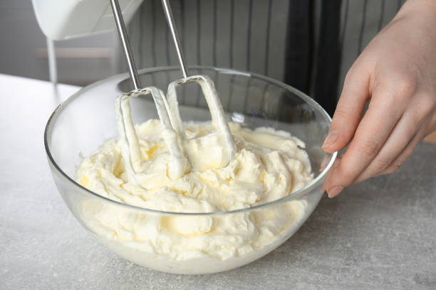 istock Woman whipping white cream with mixer at light grey table, closeup 1456832069