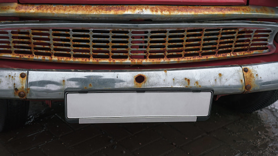 Empty numberplate fixed under rusty car grid. Old licence plate with mockup space.