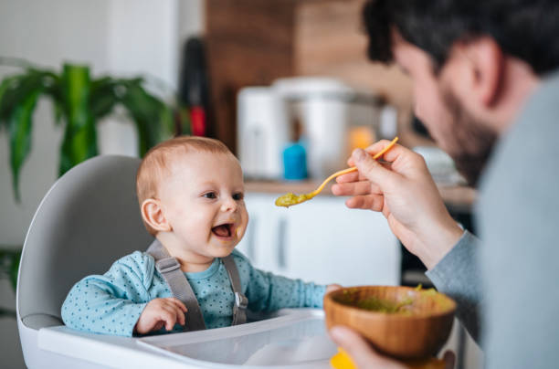 istock Father is feeding baby son in high chair. 1456835166