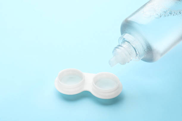 istock Dripping solution into case with contact lenses on light blue background, closeup. Space for text 1456835733