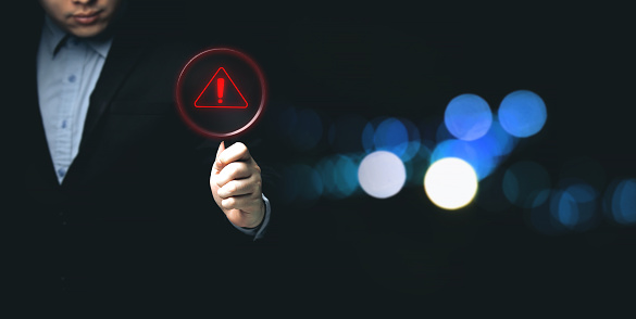 Businessman showing warning triangle warning sign showing system error. Concepts of systems, security, anti-virus, and anti-hacking access to critical data.