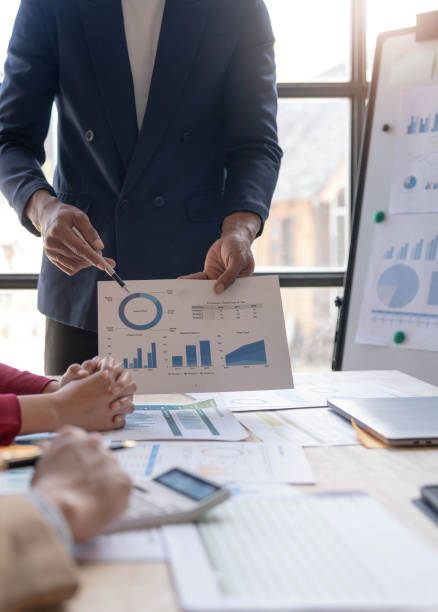 istock Business People Meeting using laptop computer,calculator,notebook,stock market chart paper for analysis Plans to improve quality next month. Conference Discussion Corporate Concept 1456849633