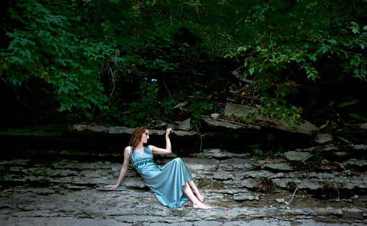 A model sits on a cliff near a creek