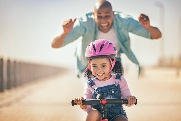 Excited father teaching girl to ride a bike in sunshine, summer fun and beach promenade outdoors. Happy kid, learning and riding bicycle with help from dad, parent and safety for healthy development padre emocionado enseñando a la niña a andar en bicicleta bajo el sol, la diversión del verano y el paseo marítimo al aire libre. niño feliz, aprendiendo y andando en bicicleta con la ayuda de papá, padres y seguridad para un desarrollo saludable