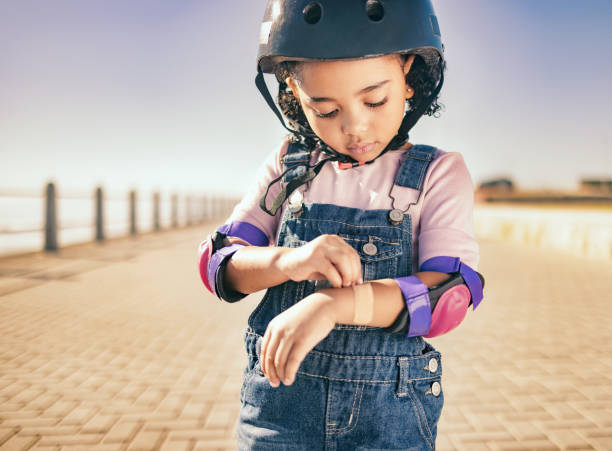 Cycling injury, arm bandage and child in street with bruise after fall or accident. First aid, bandaid and hurt city girl with safety helmet after playing, sports or fitness exercise alone on road. lesión en bicicleta, vendaje en el brazo y niño en la calle con moretón después de una caída o accidente. primeros auxilios, curitas y lastimar a una niña de la ciudad con casco de seguridad después de jugar, practicar deportes o hacer ejercicio fí