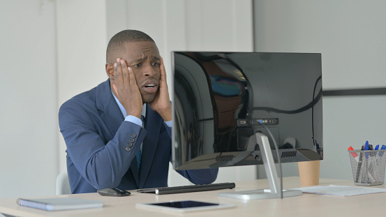 African-American Businessman Reacting to Loss While Working on Computer
