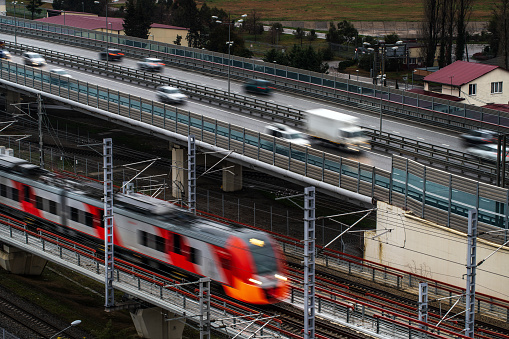 Aerial view of an electric train blurred in motion at the elevated railway and cars traffic blurred in motion at overpass road