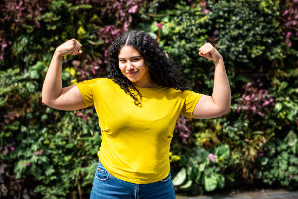 Young multiracial woman flexing muscles and looking at camera stock photo