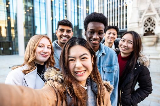 Multiracial people taking a selfie together and making funny faces - Happy friendship and diversity concepts with mixed race young best friends having fun in the city