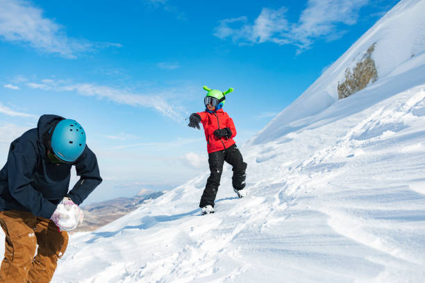 istock Father and son having fun at ski resort, playing with snow 1456858333
