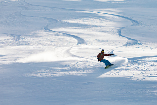 Young adult man snowboarding in mountains alone