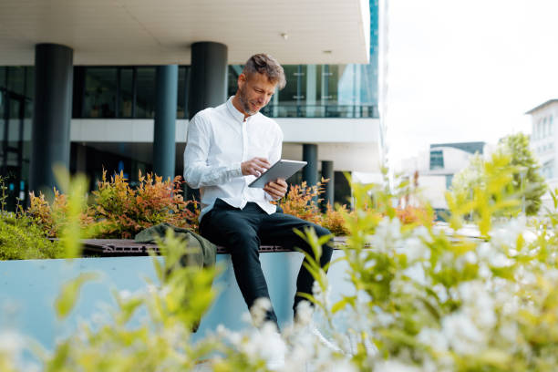 デジタルタブレットを使用する金融街のビジネスマン - digital tablet people business outdoors ストック��フォトと画像