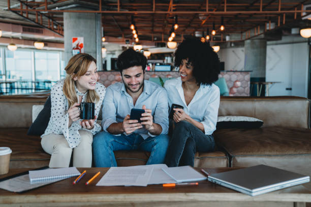 istock Three colleagues looking at a smartphone together during a break at the office 1456858689