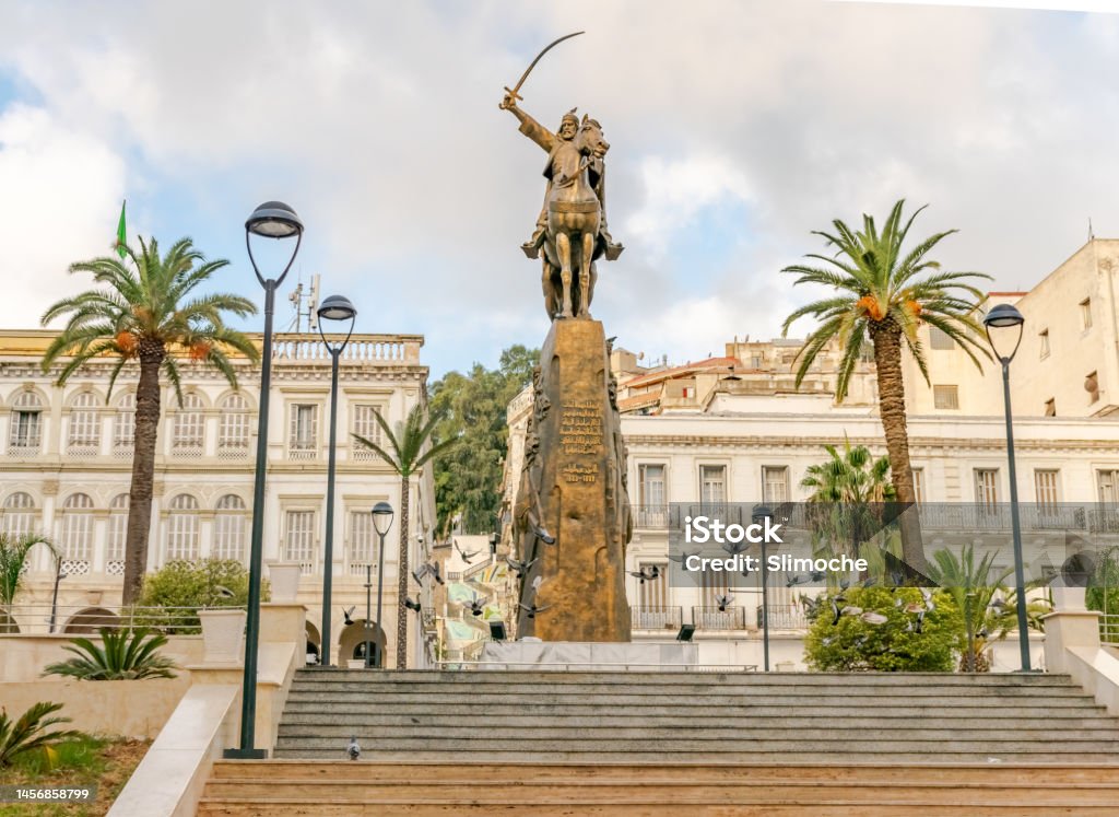 El Amir Abdelkader statue with flying pigeons and palm trees Algiers, Algeria - October 10, 2022: Emir abdelkader place, Larbi Ben M'hidi and Colonel Haouas road. Algiers city town hall building. Algiers - Algeria Stock Photo