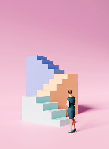 Woman stands in front of a staircase in different colors.  She is about to walk up the stairs. Concept of standing in front of a challenge and finding the right solution and courage to move on.