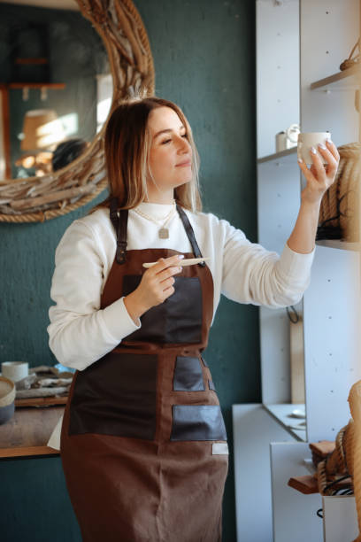 istock Smiling young woman wearing apron in cozy pottery studio 1456861718