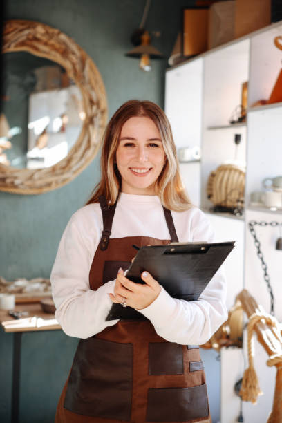 istock Smiling young woman wearing apron in cozy pottery studio 1456862484