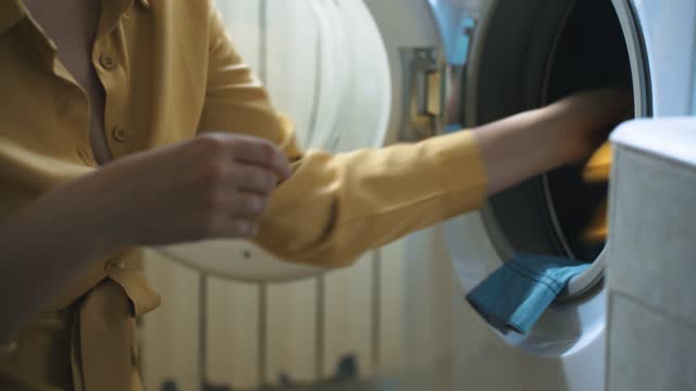 Woman loading clothes into washing machine.