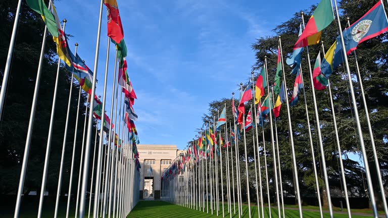 Geneva, Switzerland, January 2023. Footage with wide angle lens and low angle shot: iconic image of the headquarters of the united nations. In the courtyard the flags of the member states.