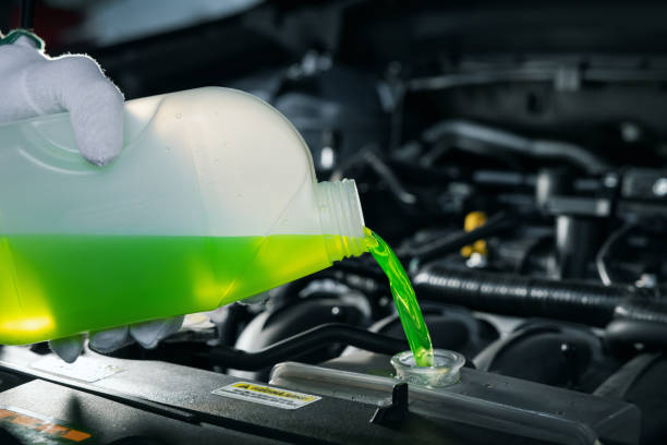 pouring antifreeze coolant liquid into car engine radiator stock photo