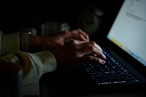 istock Anonymous woman working on laptop at night 1456865545