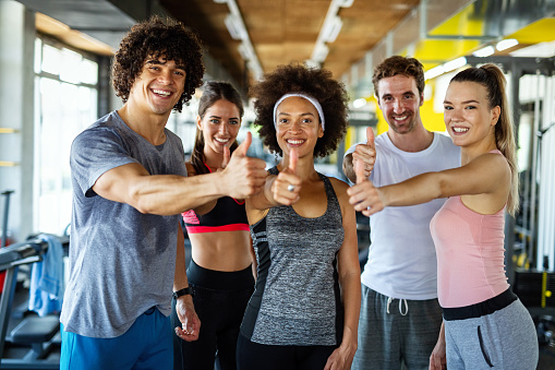 Group of sportive fit people working out in a gym. Multiracial friends exercising together in fitness club.