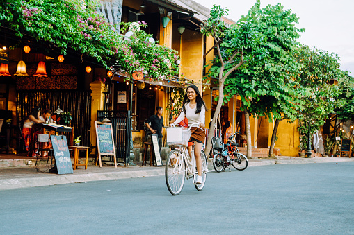 happy vietnamese woman riding bicycle in old town of Hoi An, Vietnam