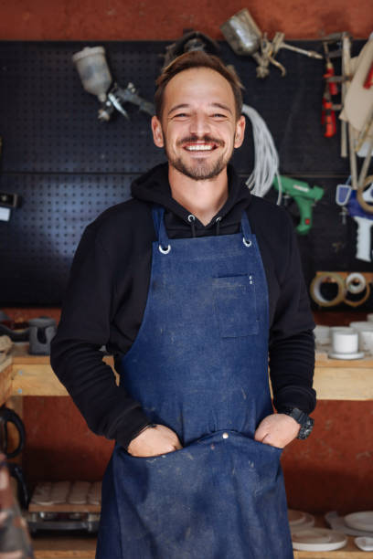 Carpentry Owner in Workshop Portrait of mature bearded carpenter posing confidently with arms crossed standing in woodworking shop and smiling happily looking at camera carpenter portrait stock pictures, royalty-free photos & images