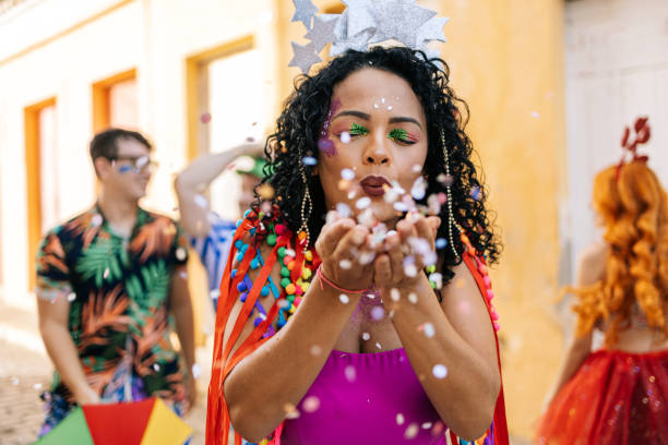 бразильский карнавал. молодая женщина, наслаждающаяся карнавальной вечеринкой, дующая конфетти - carnival parade стоковые фото и изображения