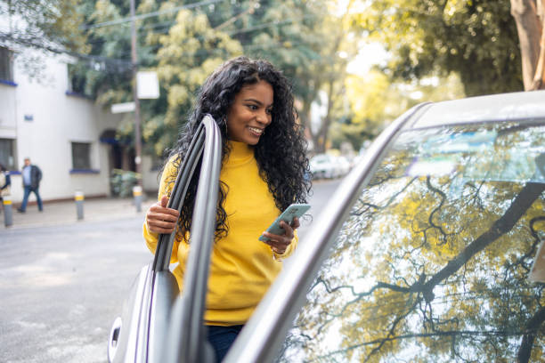 istock Young woman texting while opening the car door 1456874441