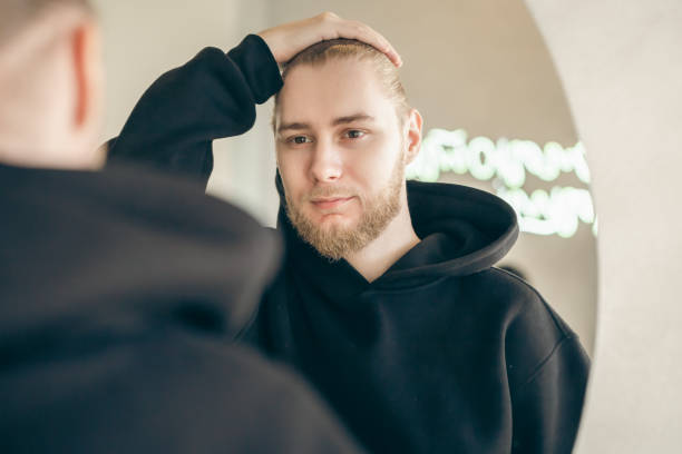 istock An attractive young man with a beard looks at himself in the mirror. 1456875559