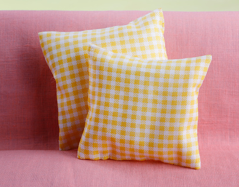 Yellow checked pillow on pink sofa