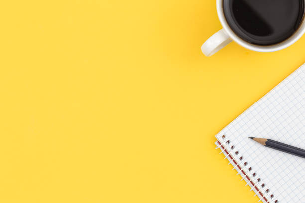 istock Empty notebook with cup of coffee on a yellow background, flat lay. 1456876152