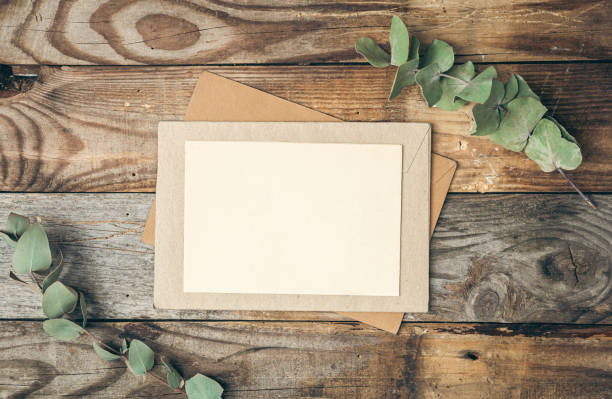 istock Blank paper and envelope on wooden background with eucalyptus twigs, flat lay. 1456876492