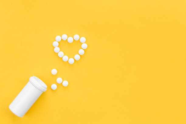 istock Scattered heart shaped pills on yellow background, flat lay. 1456877316