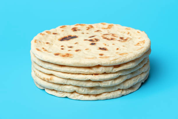 Naan bread isolated on blue background. Stack of indian flatbread. Stack of indian flatbreads minimalist on a blue table. Homemade naan bread, asian traditional food. pita bread isolated stock pictures, royalty-free photos & images