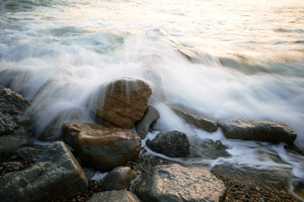 Rocky coastline and smooth water waves blurred by long exposure in evening