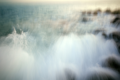 Rocky coastline and smooth water waves blurred by long exposure in evening